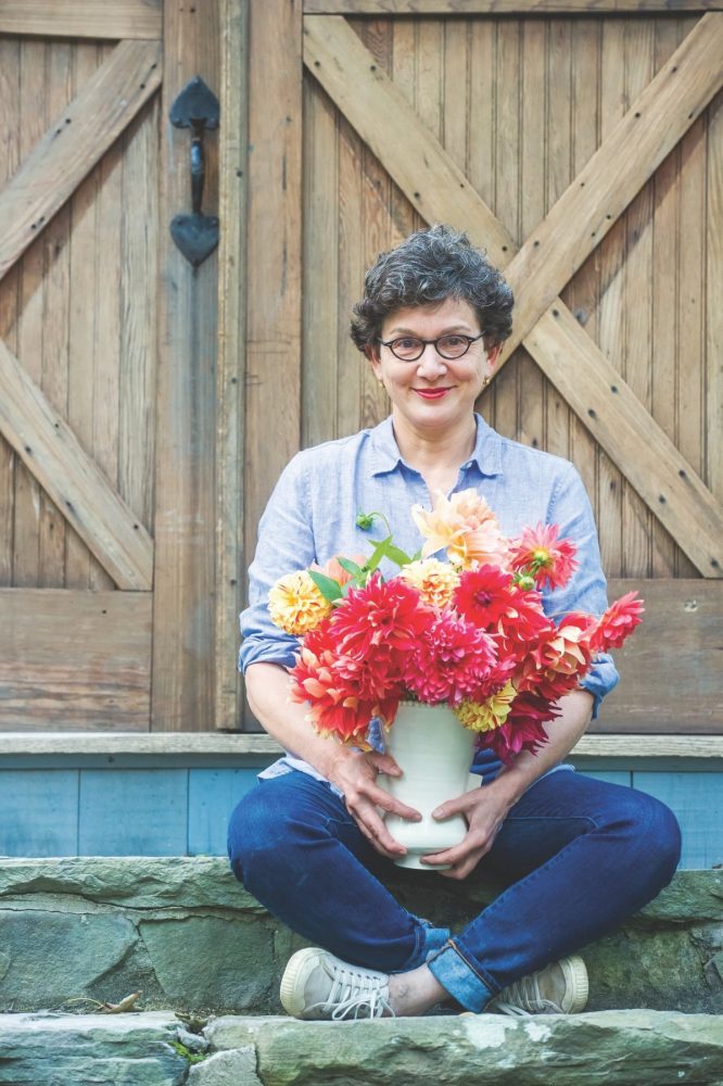 Frances Palmer holding one of her ceramic vases filled with dahlias from her garden