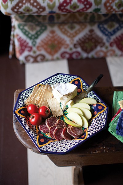 Hors d’oeuvres are as simple as fruit, cheese, crackers, and summer sausage on a majolica serving plate.