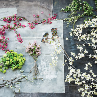 assorted flowering branches with white, green, hot pink, and light pink flowers, spread out on a wooden work surface
