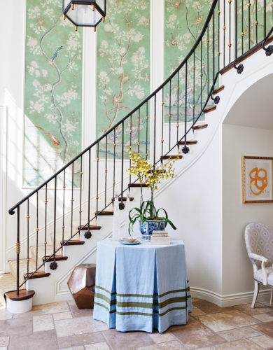 Garden-inspired chinoiserie panels decorate the entryway of a California home. A pale-blue tableskirt with olive trim combines the colors of sky and garden.
