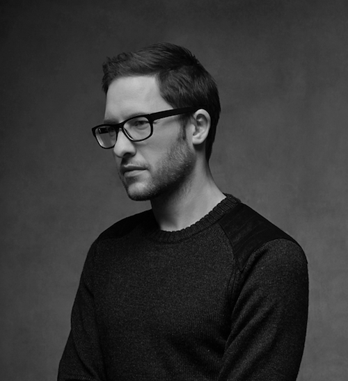 black and white portrait of jewelry designer Matthew Campbell Laurenza wearing a simple long-sleeved black shirt and black rimmed glasses