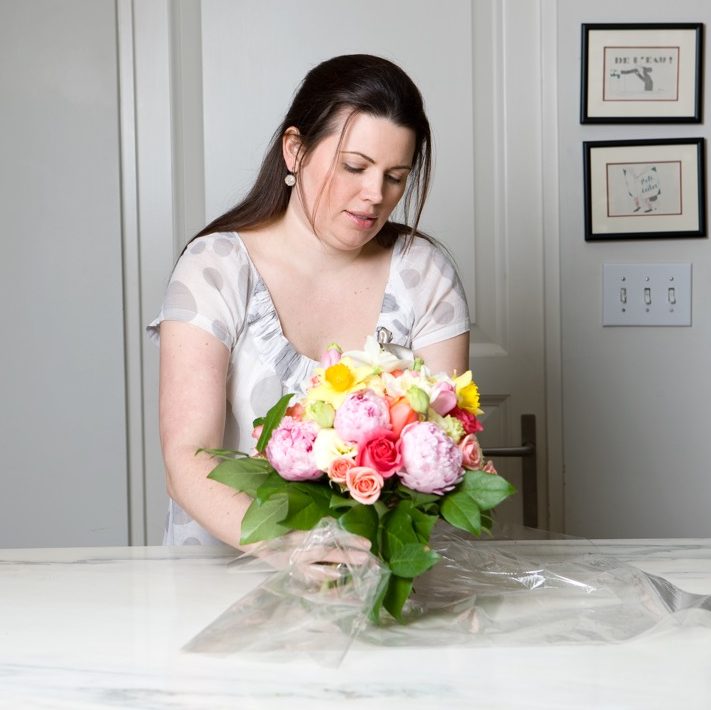 Mimi Brown wraps plastic around the bottom of the bouquets.