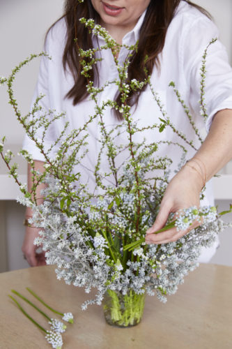 Filling in dark spots in silver and white arrangement with flowers and leaves of white muscari