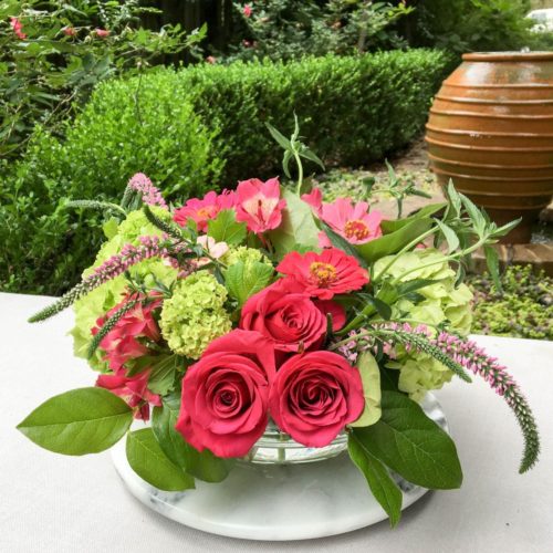 Pink and green summer centerpiece flower arrangement with roses, hydrangeas, zinnias, and veronica.