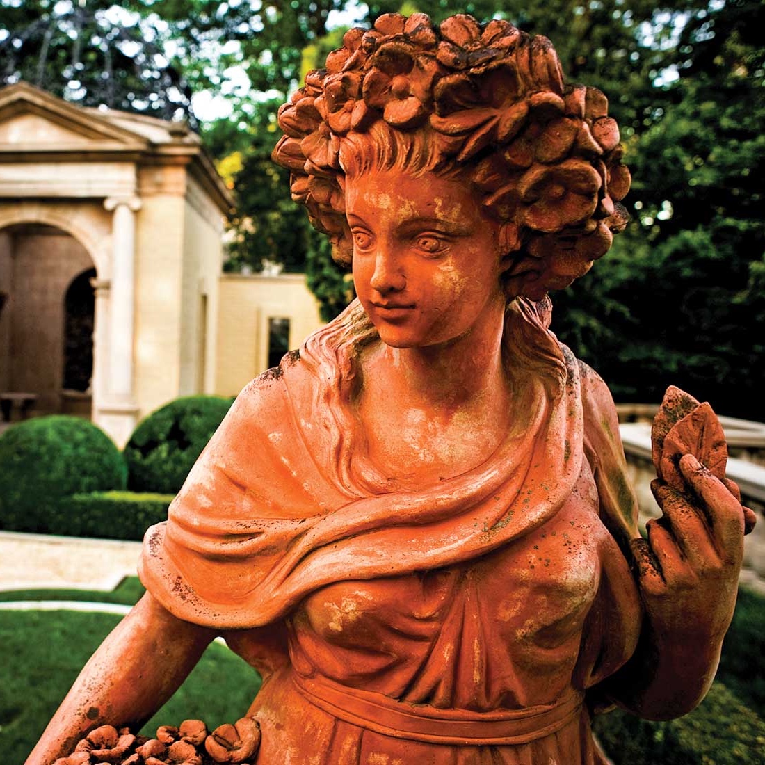 A terra-cotta maiden in a French-style garden 