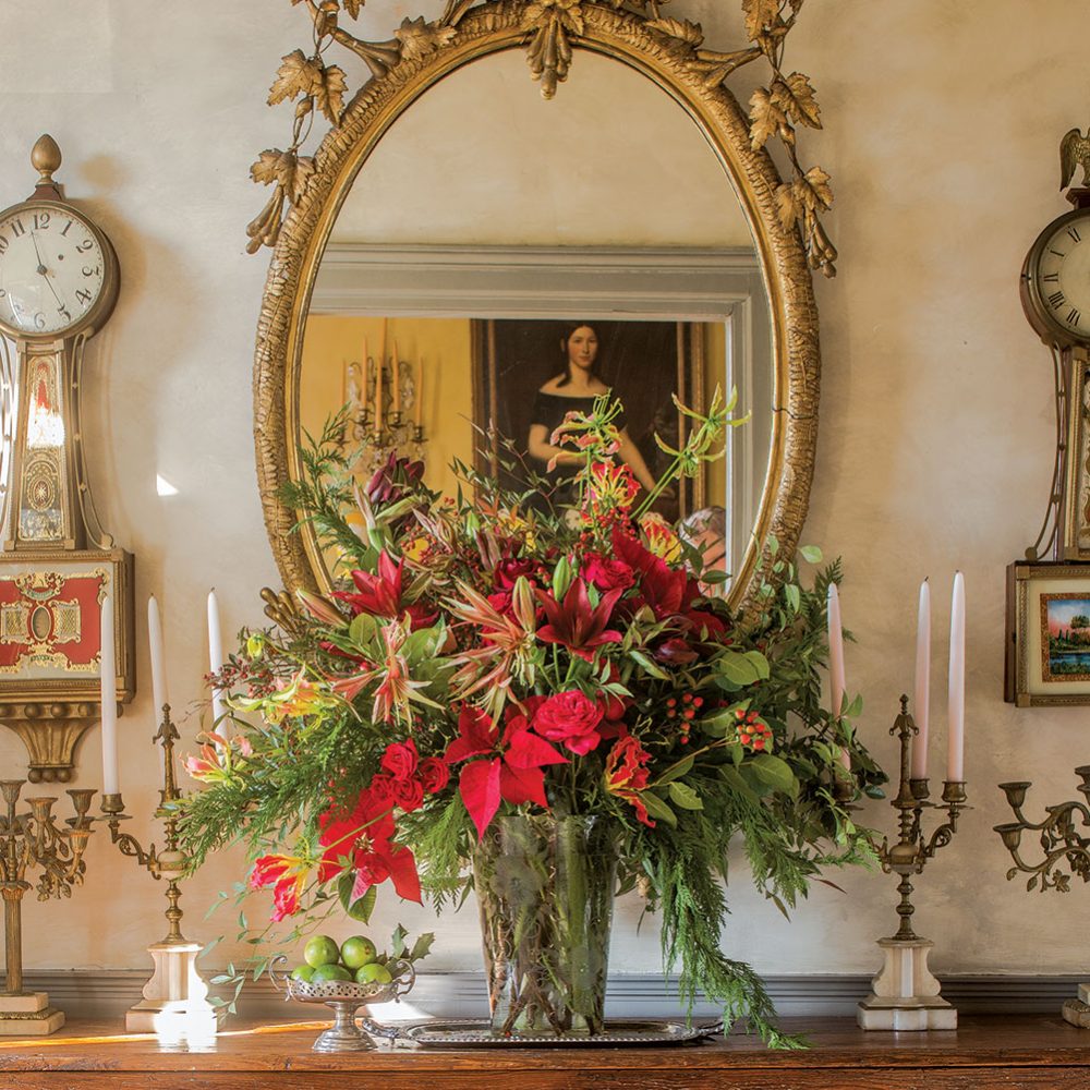 Vase of poinsettias, lilies, amaryllis, roses, evergreens, and berries makes a stately focal point in an entryway