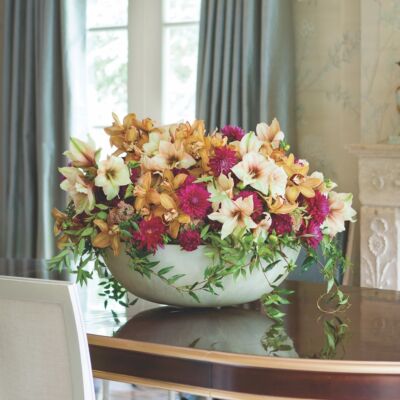White ceramic bowl of Mocca amaryllis, dahlias, cymbidium orchids, dianthus, and jasmine vine.