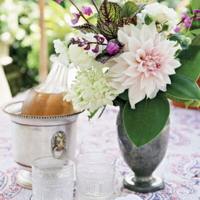 charlotte moss entertains, chilled champagne in an ice bucket, floral arrangement in a green vase, napkins, and glasses