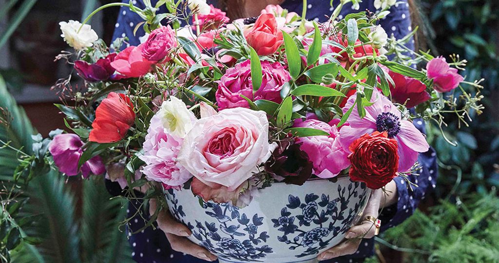 a blue-and-white bowl of flowers in shades of pink featuring