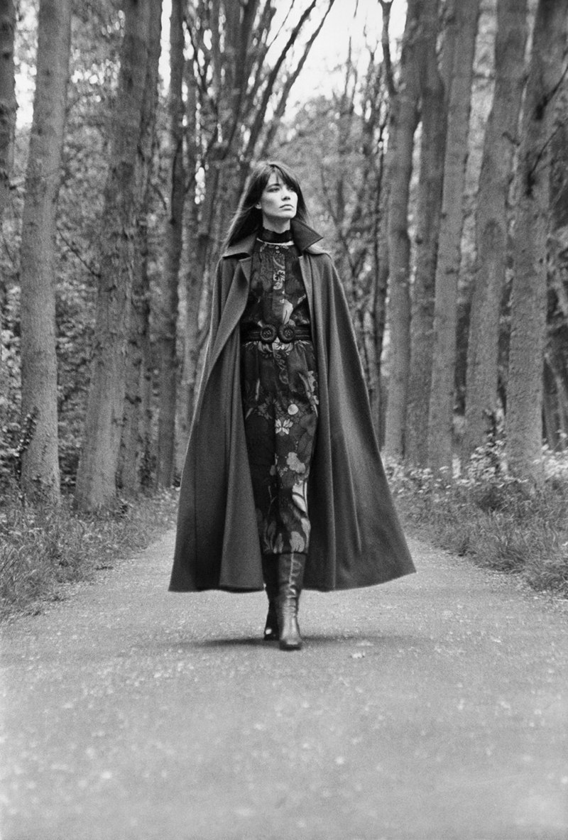 Black-and-white photo of Françoise Hardy walking down a tree-lined path