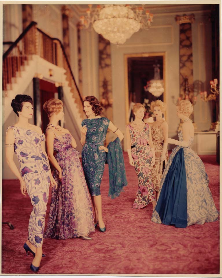 Six women model botanical-print gowns in an opulent setting
