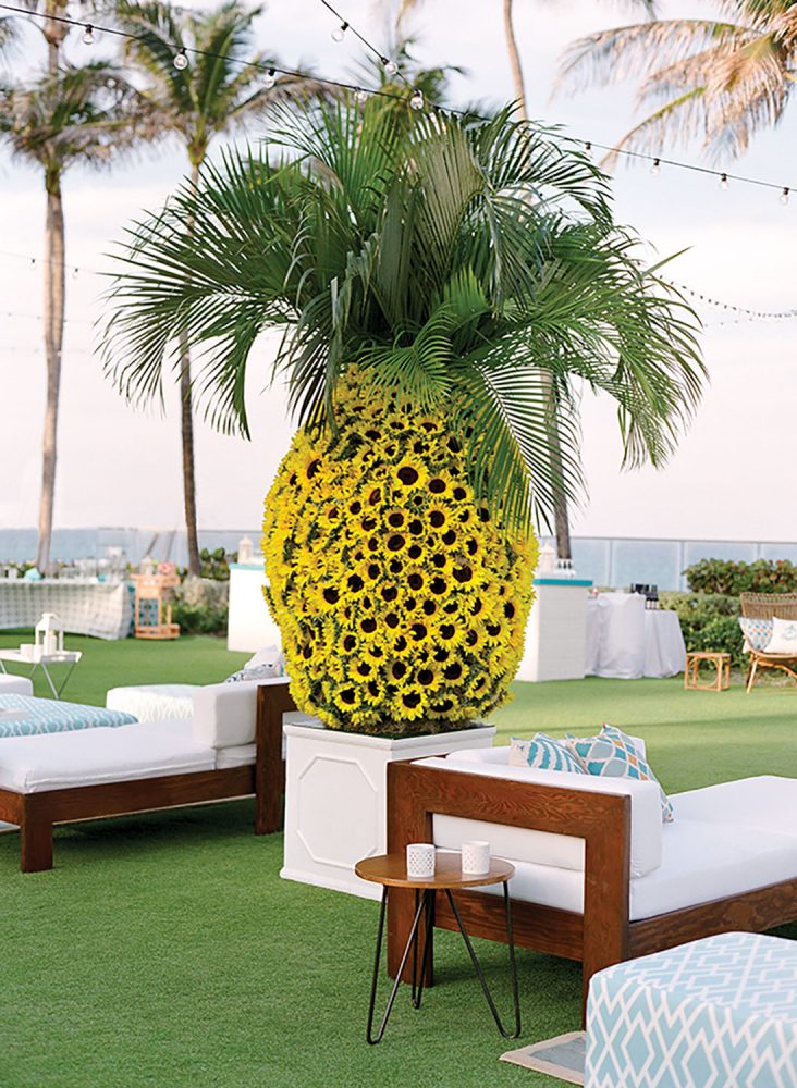 Pineapple shaped arrangement of sunflowers and palm fronds.