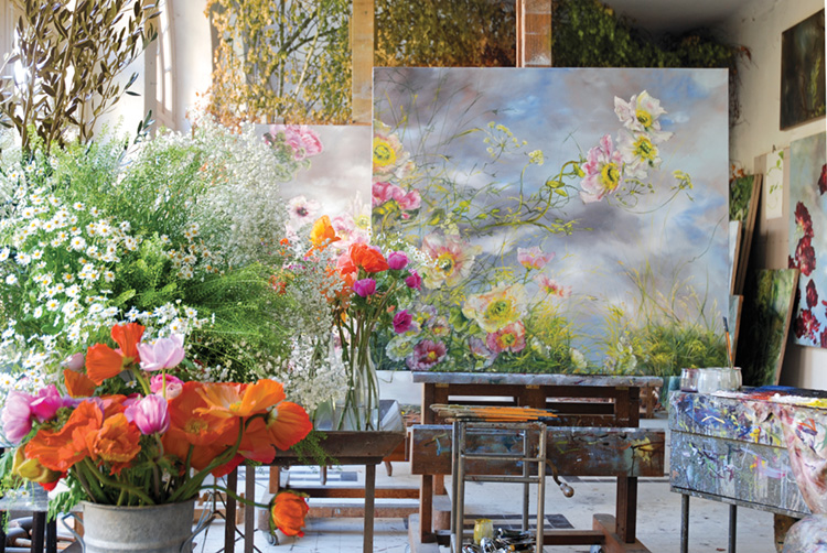 Vases of bright pink and orange flowers alongside paintings in Claire Basler's studio