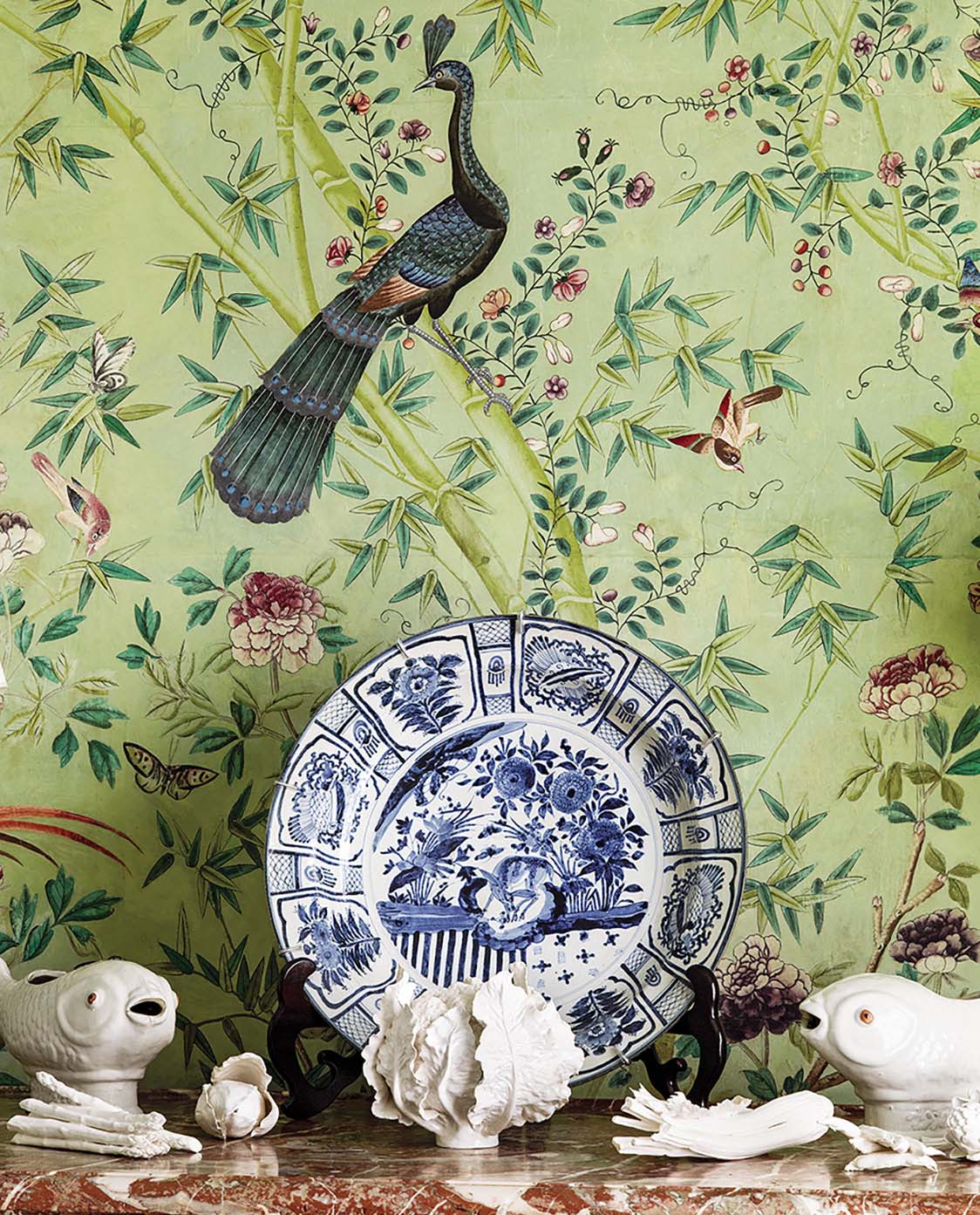 Vignette with white porcelain objects, Blue-and-white plate. Chinoiserie wallpaper.