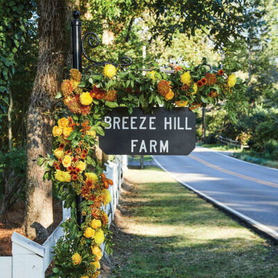 Sign for Breeze Hill Farm decorated with orange and yellow flowers
