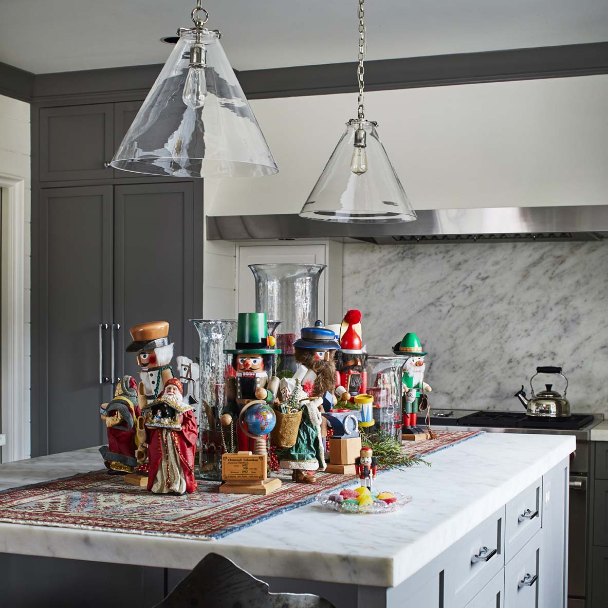 For the holiday home tour, a large mable-topped kitchen islands holds a collection of nutcrackers displayed on a small oriental runner