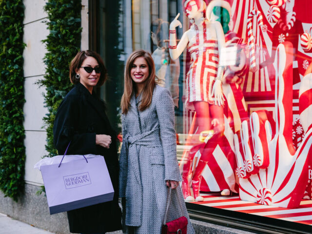 Alison Bruhn and Delia Folk stand outside Bergdorf Goodman in New York with a shopping bag.