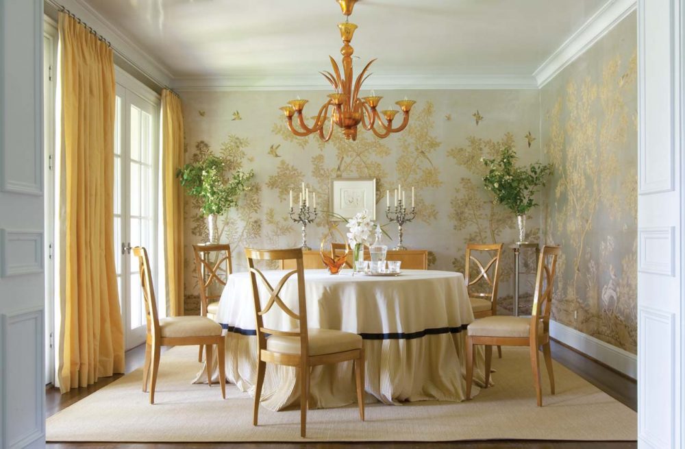 Dining room with golden-hued scenic wallpaper and gold chairs.