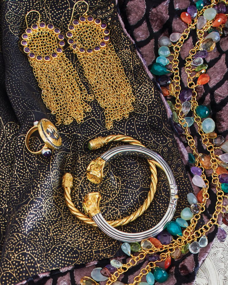 Pictured: assortment of J. Catma jewelry, including old-toned chandelier earrings, bracelet cuffs, rings, necklaces made from colorful beads