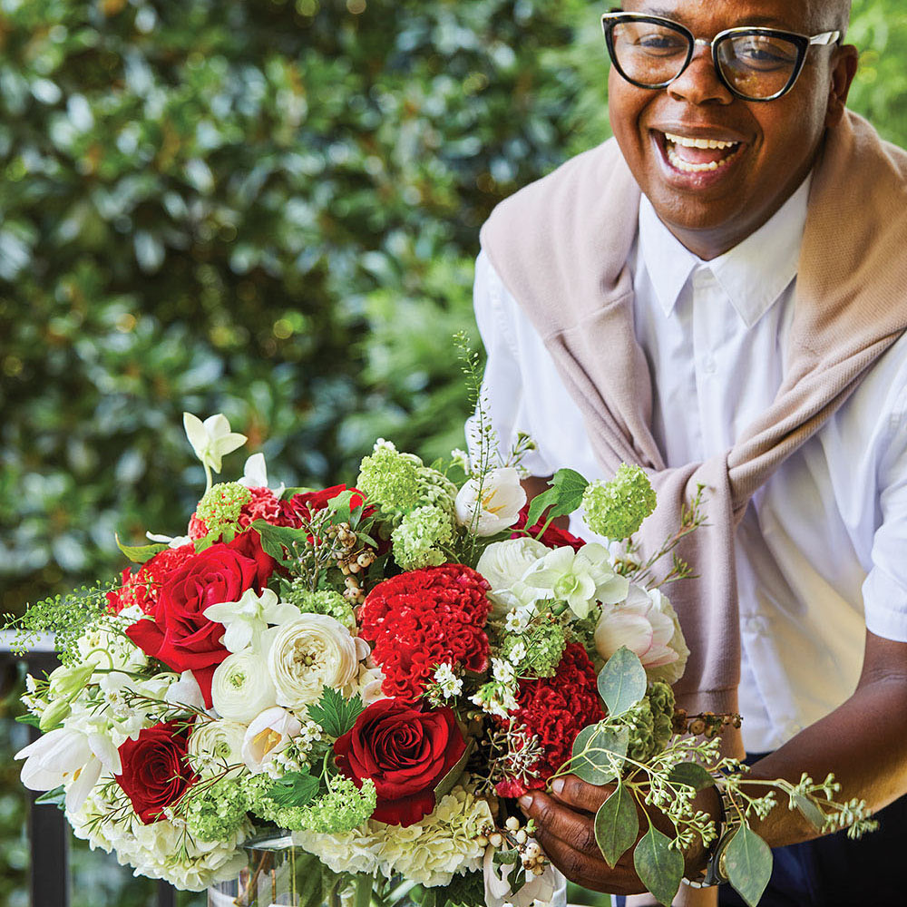 Canaan Marshall smiles big as puts the finishing touches on the red, white, and green holiday floral arrangement