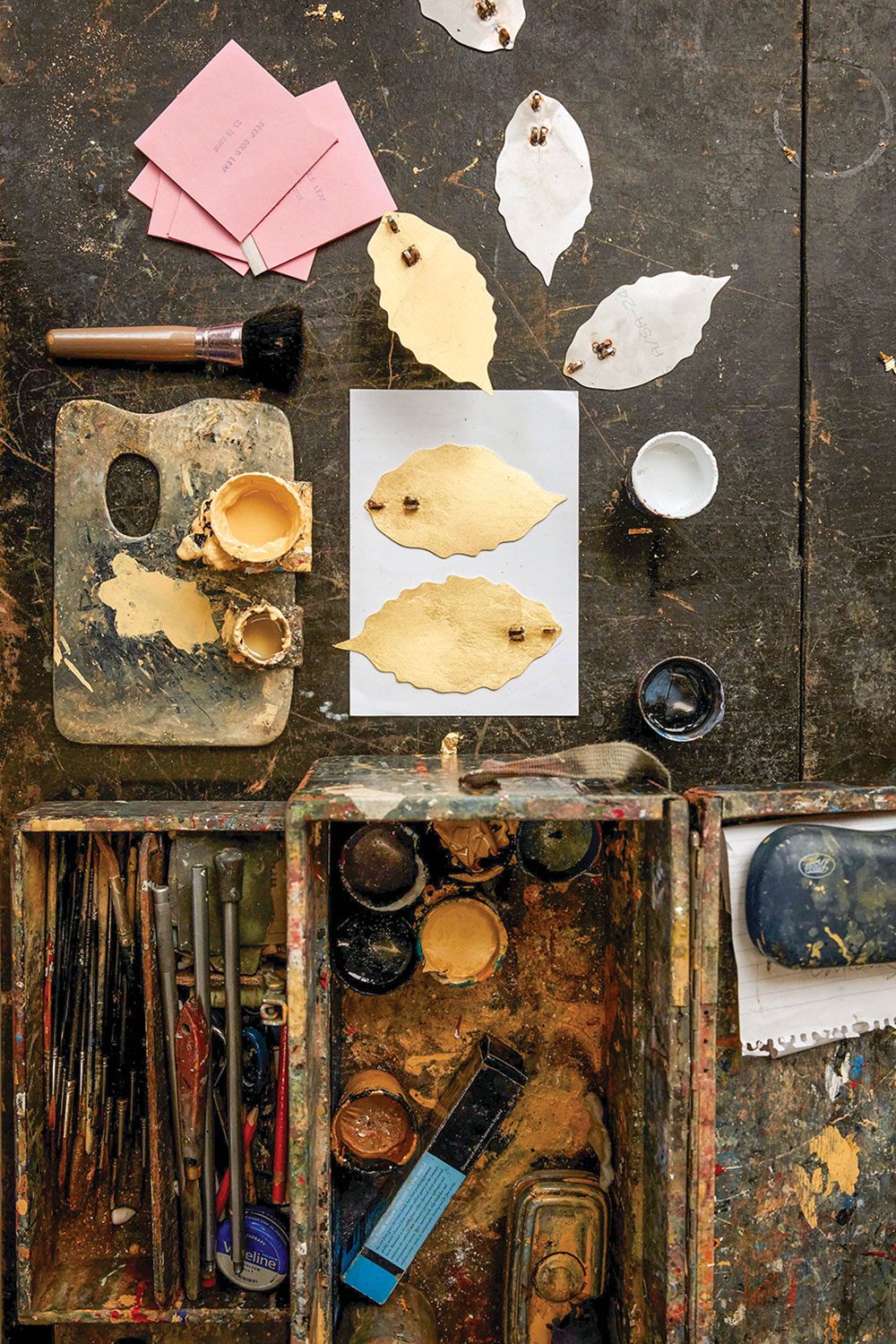 leaf cutouts and artist tools, including a palette, brushes and cups of paint
