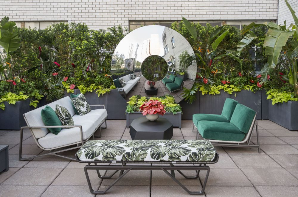 In New York, a reflective disc-like sculpture by David Harber stands before an outdoor seating area on the rooftop terrace adjoining the Christopher Peacock showroom at the Decoration & Design Building