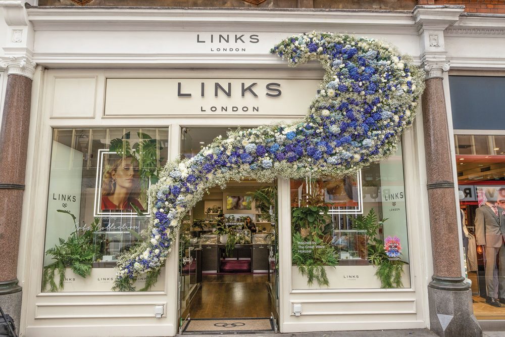 Storefront of Links London decorated with a swoosh of purple and white flowers for Chelsea Flower Show