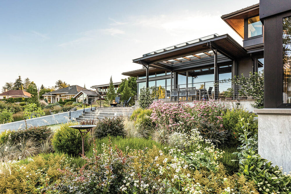 Meadow-like garden with steps up to a covered dining deck on a modern home in Washington State.