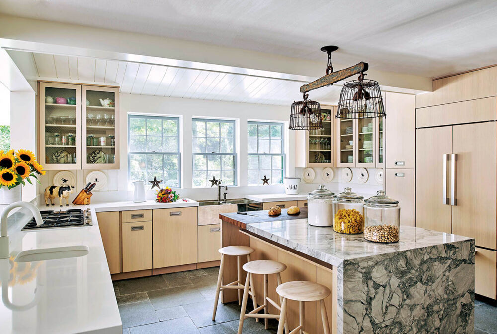 Kitchen with natural wood cabinets and marble and butcher-block island. Light fixture made from old cattle yoke and metal baskets hangs over island.