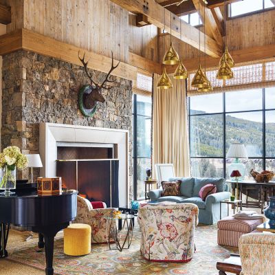A high ceiling with wooden beams hangs over a living room looking out on rolling hills.
