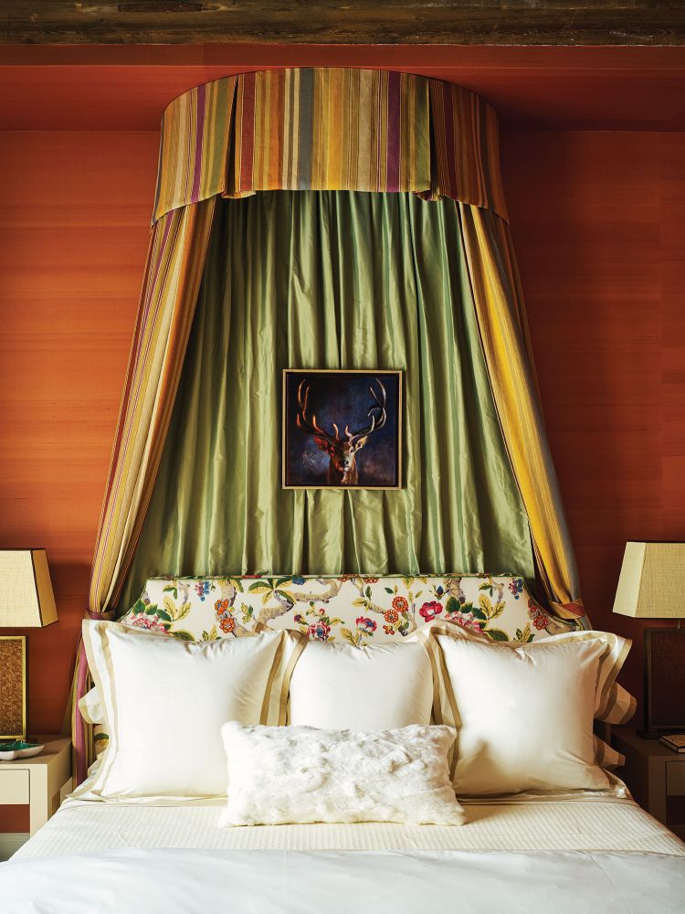 A dramatic green and striped bed canopy hangs over a cream colored bed.