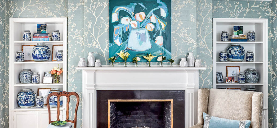 Fireplace with white mantel flanked by built-in bookcases filled with blue-and-white porcelain.