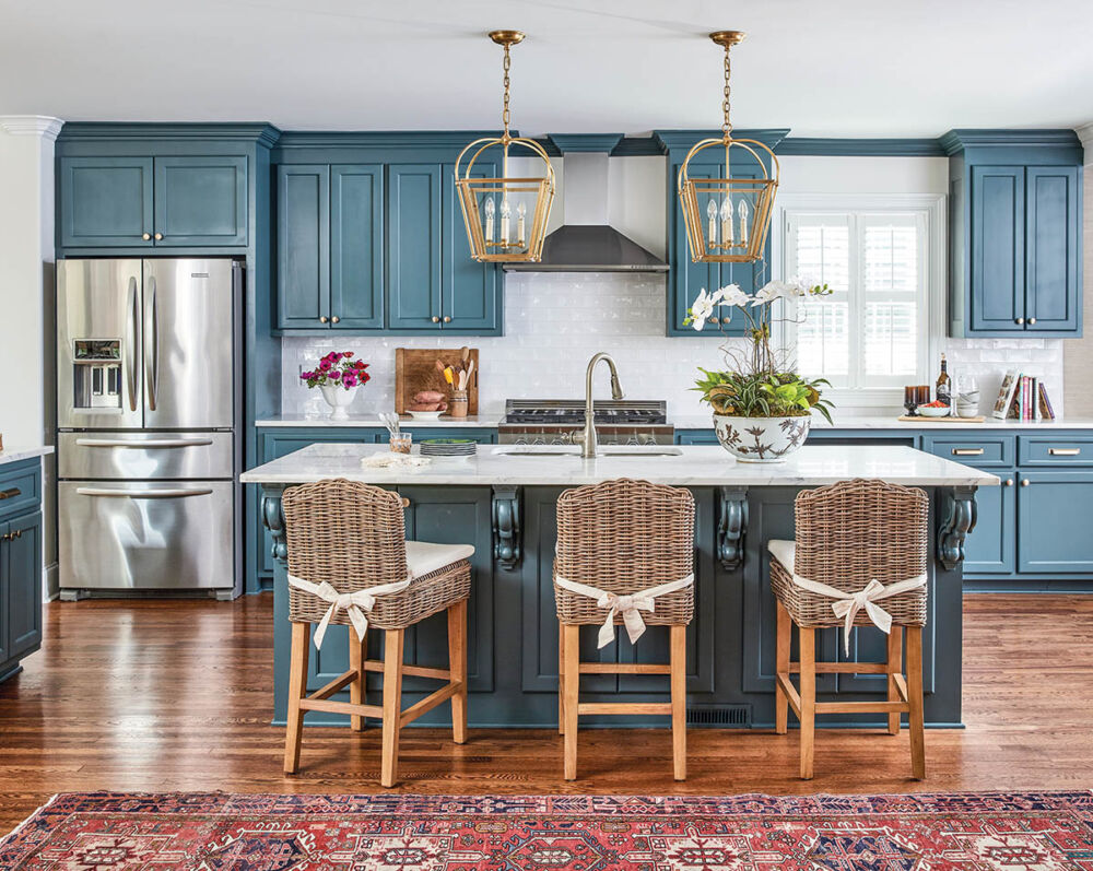 Kitchen with blue cabinets and island, brass light pendants over island.