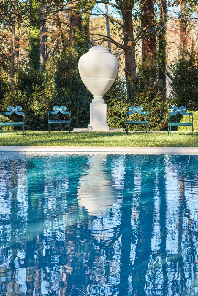 Oversized casting of an Italian olive jar behind the swimming pool in a garden designed by John Howard.