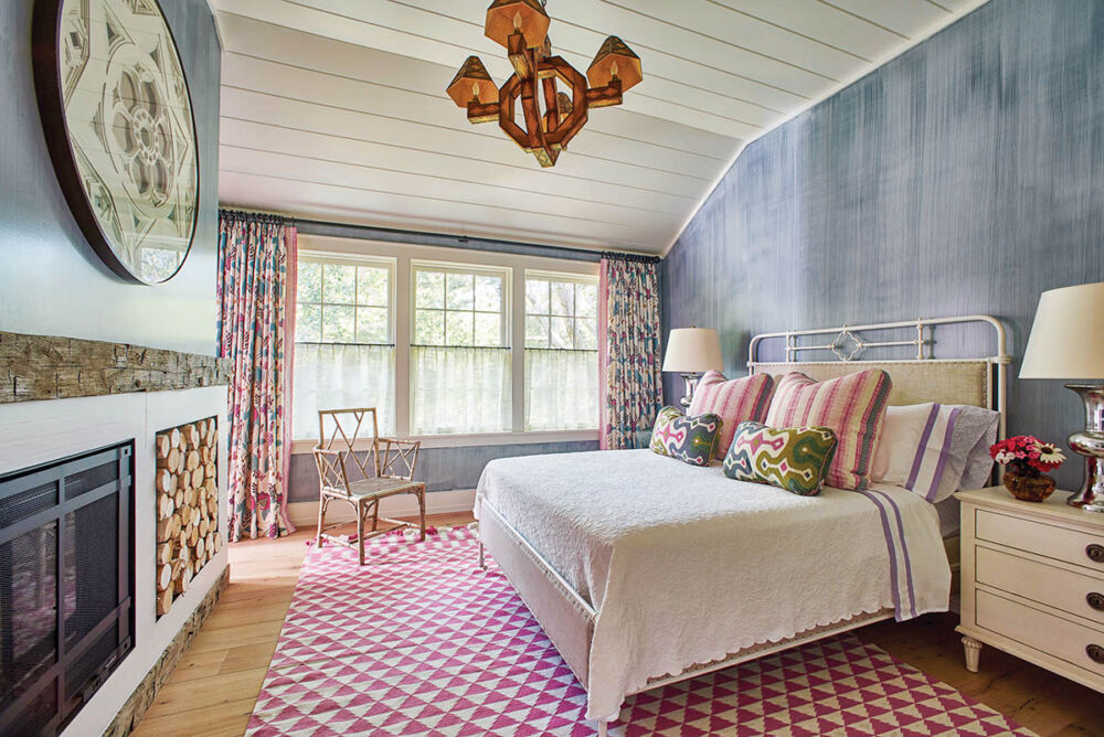 Guest bedroom with blue walls, iron bed, and pink and white rug.