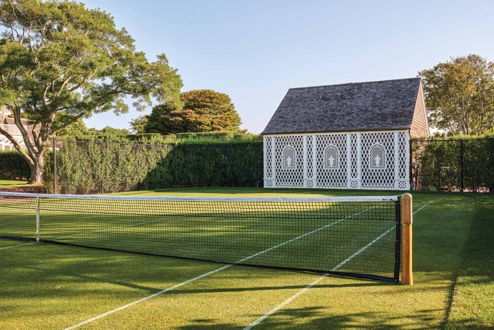 A grass tennis court gleams in the yellow sunset.