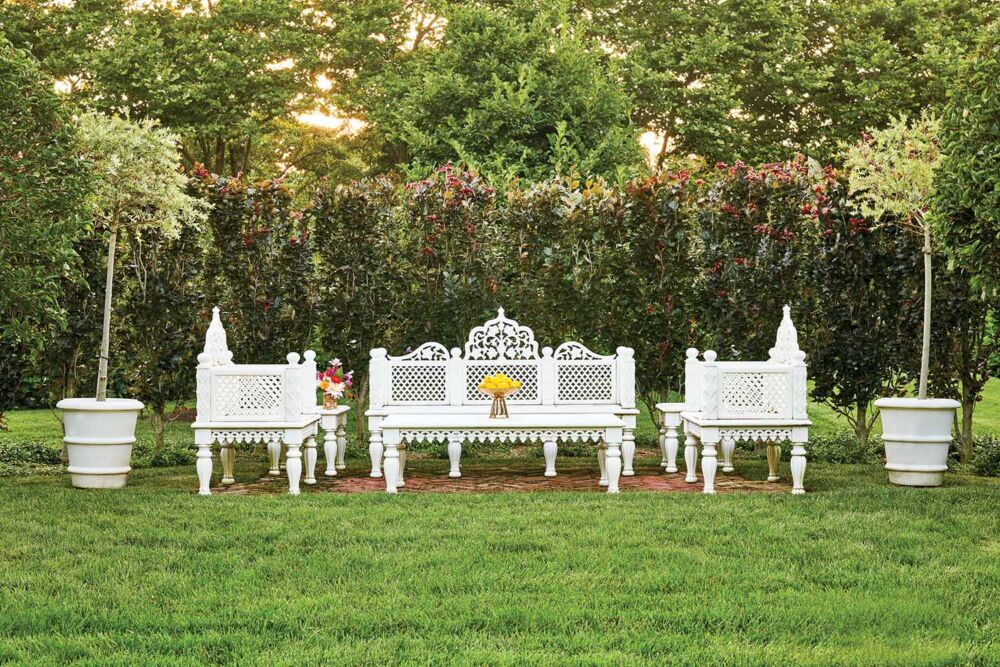 White Indian inspired outdoor furniture sit in a green lawn.