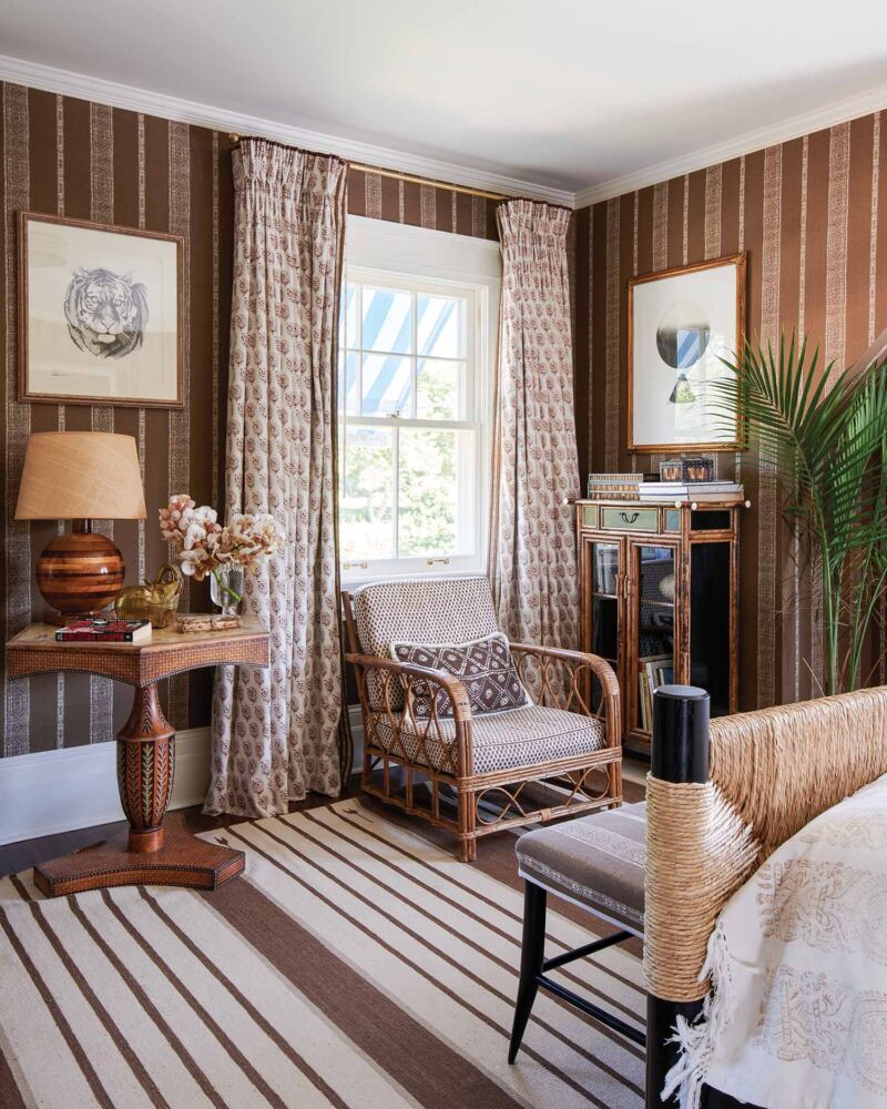 Brown striped wallpaper and rugs cover a safari inspired bedroom.