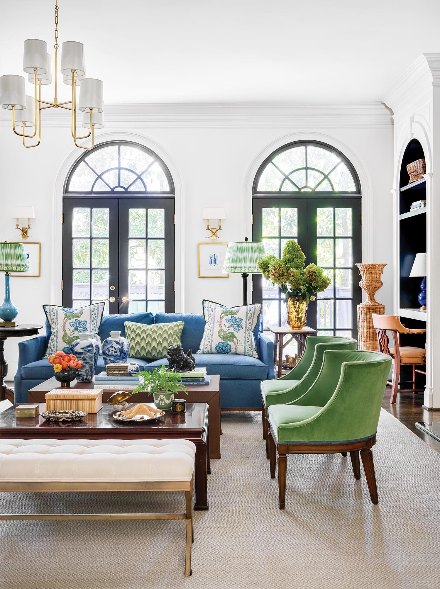 Bright blue and green furniture fill a high ceilinged white room.
