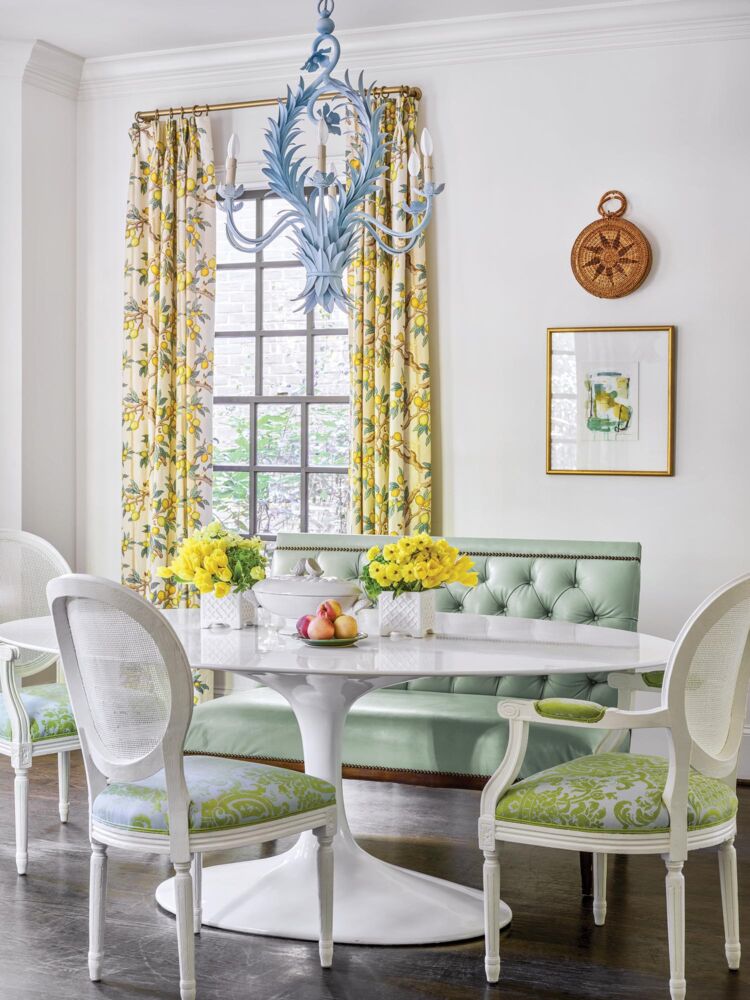 A bright green booth is matched with white and green chairs in a cheery white kitchen.