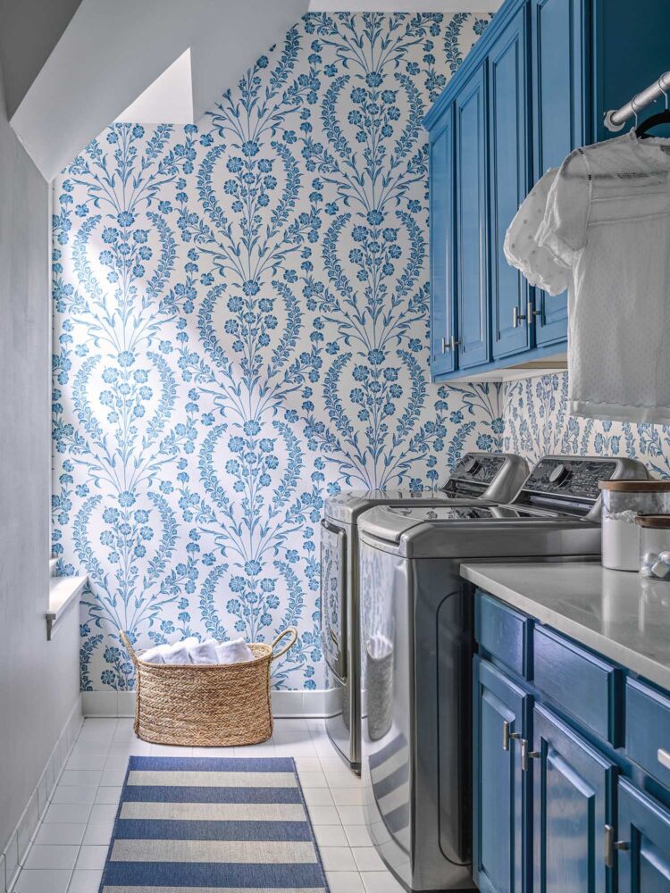 A blue floral wallpaper matches blue painted cabinet in this unique laundry room.