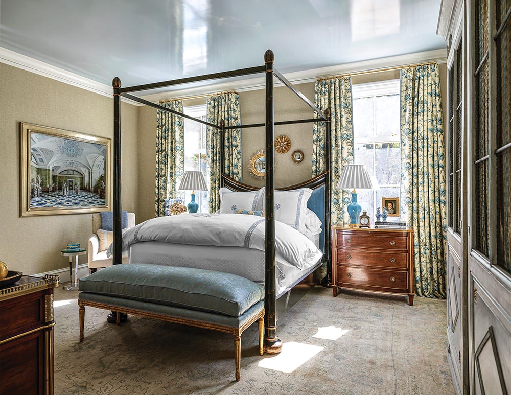 Four poster bed flanked by windows, with a bench at foot in the "Rhapsody in Blue" guest bedroom designed by Beth Webb and Tristan Harstan for the Flower Atlanta Showhouse.