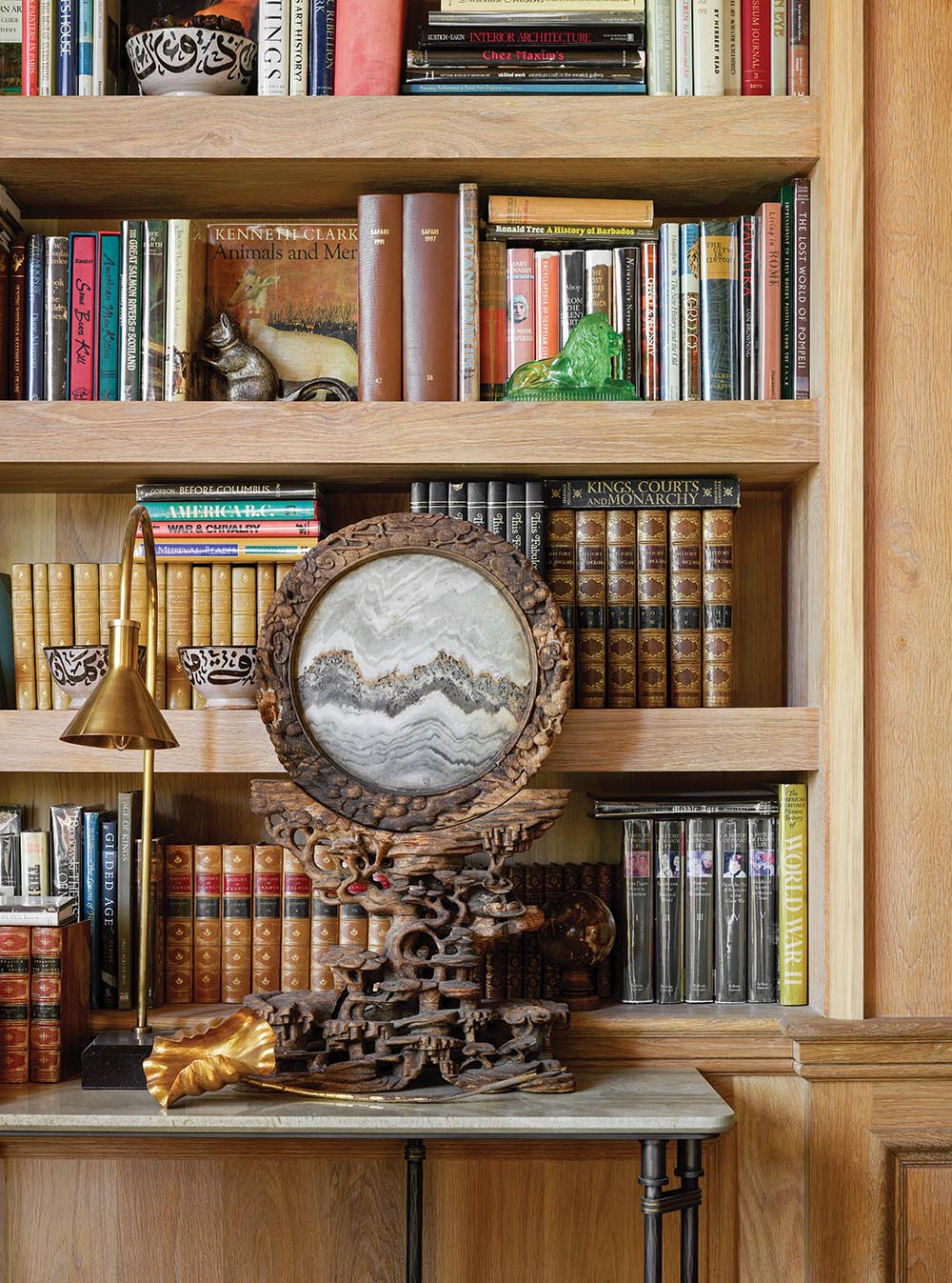 Ornately mounted Chinese stone slice on table in front of bookshelves in Flower Atlanta Showhouse library.