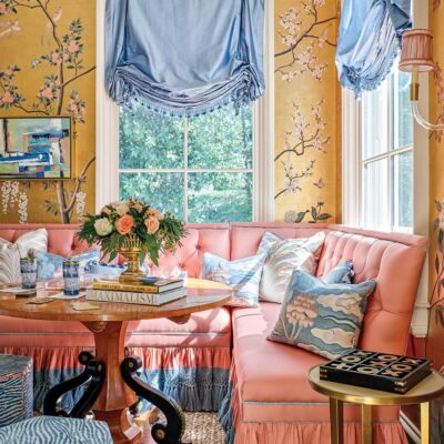 Mallory Mathison Glenn used contrasting materials like a chunky jute rug and dark woods to balance the Gracie wallpaper, dressmaker window treatments from The Shade Store, and tufted banquettes from Lillian August in this sitting room at the Flower Atlanta Showhouse