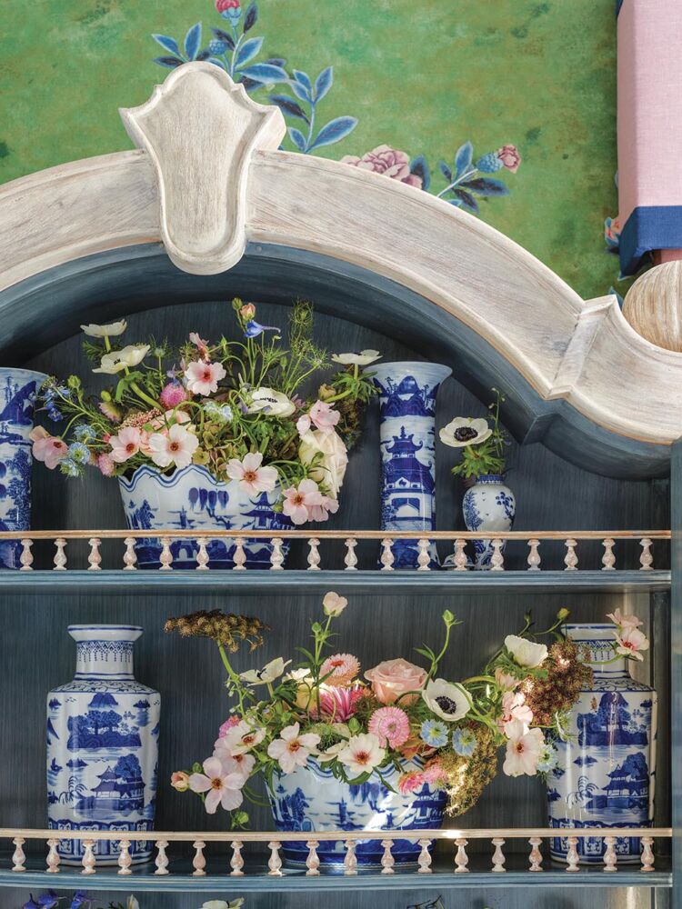Arrangements of flowers in blue and white compotes and vases on shelves in Lisa Mende designed bedroom at the Flower Atlanta showhouse