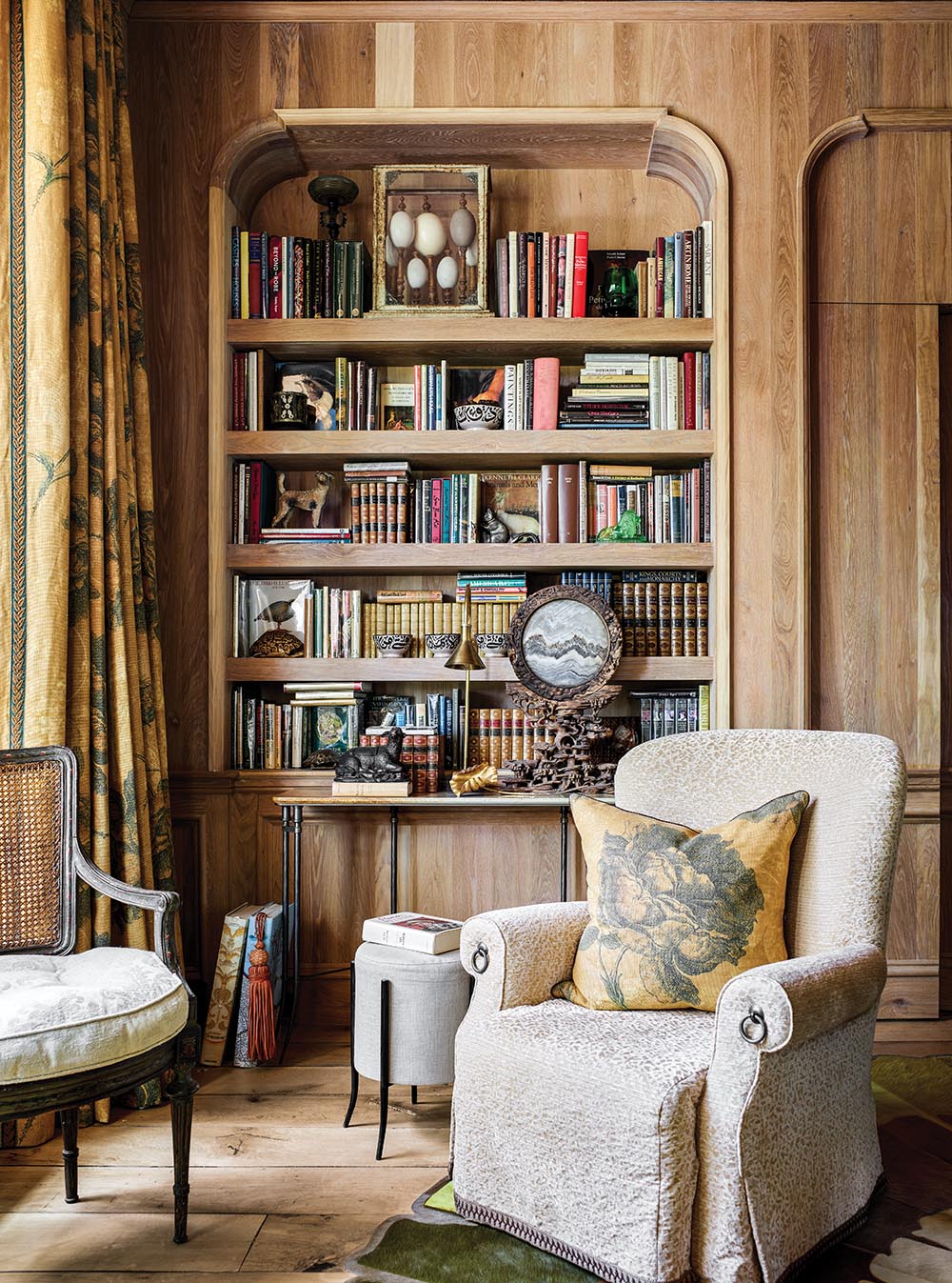 Pair of chairs in front of oak paneled wall with built in bookcases in library of the Flower Atlanta Showhouse.