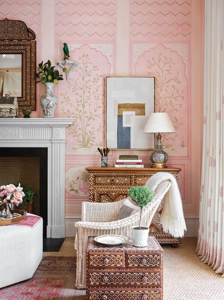 Sitting area in front of fireplace in primary bedroom with Indian inspired pink wallpaper.
