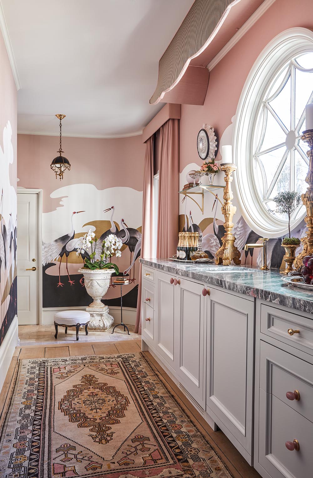Morning bar in the east gallery with rose colored wallpaper with life-size storks. Arrangement of white orchids in urn sits by the door.