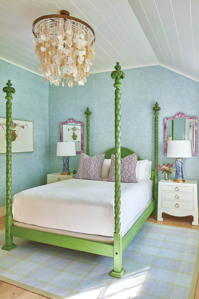 Green, four-poster bed in bedroom with sloping ceiling and blue walls.
