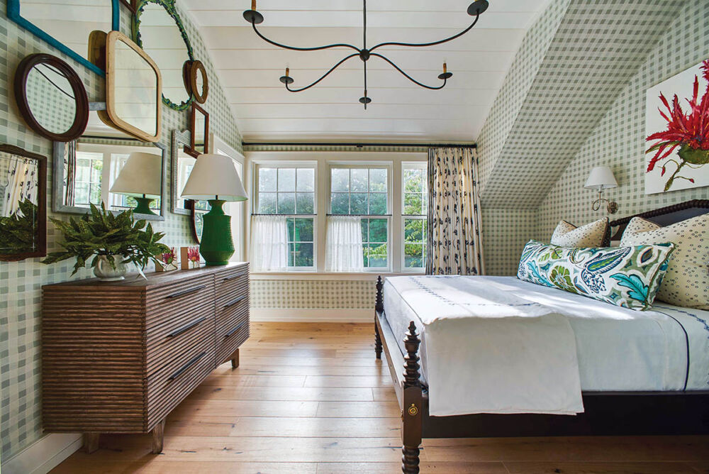 Bedroom with green-checked wallpaper on walls and part of ceiling. Overlapping mirrors cover the wall opposite the bed.
